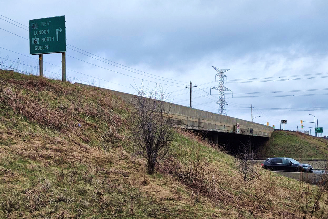 Roadside view of the Brock Road South underpass with directional sign for Highway 401 west and Highway 6 north.