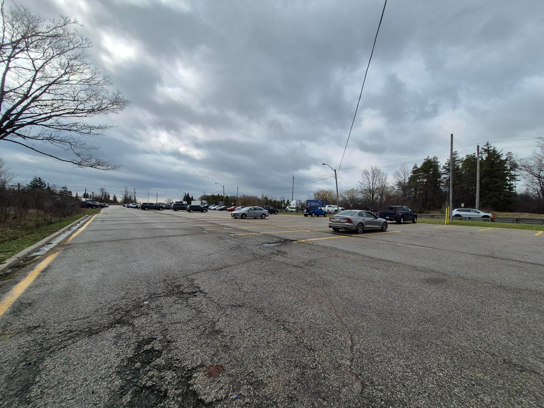 Existing carpool parking lot with several vehicles under cloudy skies.